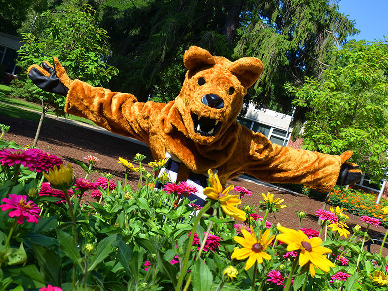 The Nittany Lion standing behind some flowers